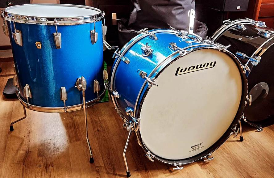 A blue drum set on a wood floor

Description automatically generated